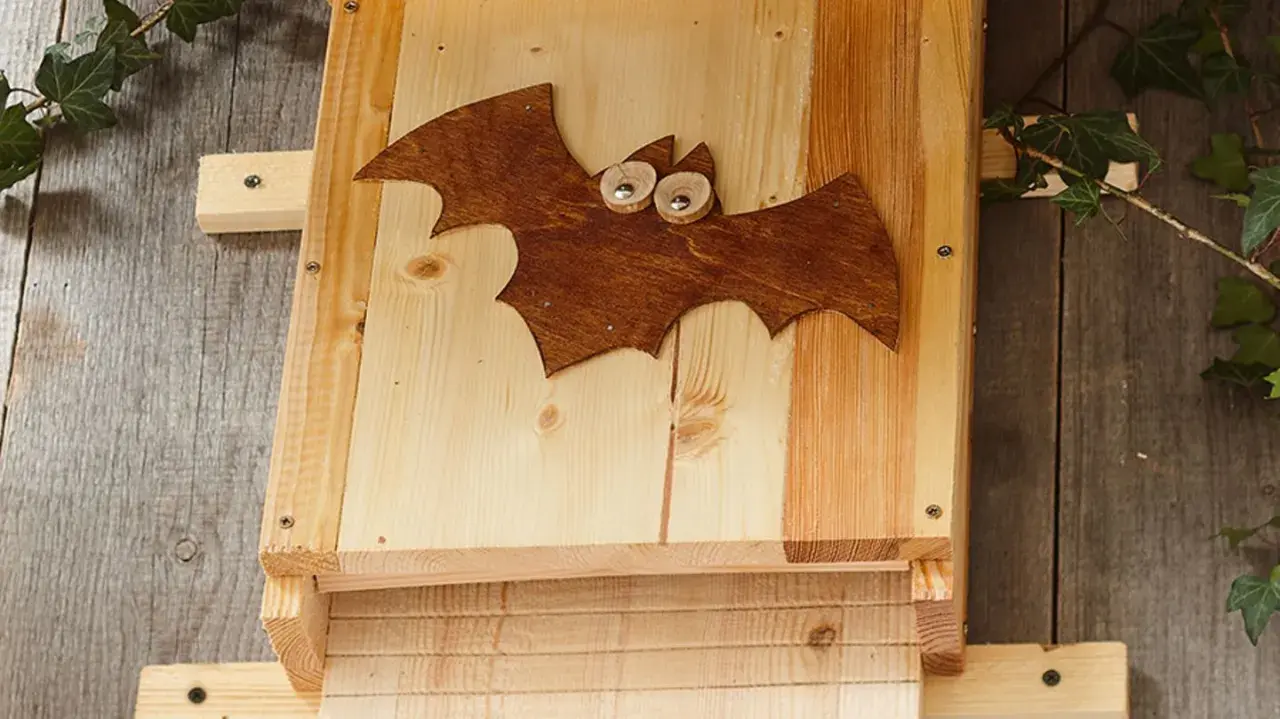 Ein selbstgebauter Fledermauskasten mit süßer Fledermaus-Deko. Perfekt für den Garten, um Fledermäuse anzulocken.