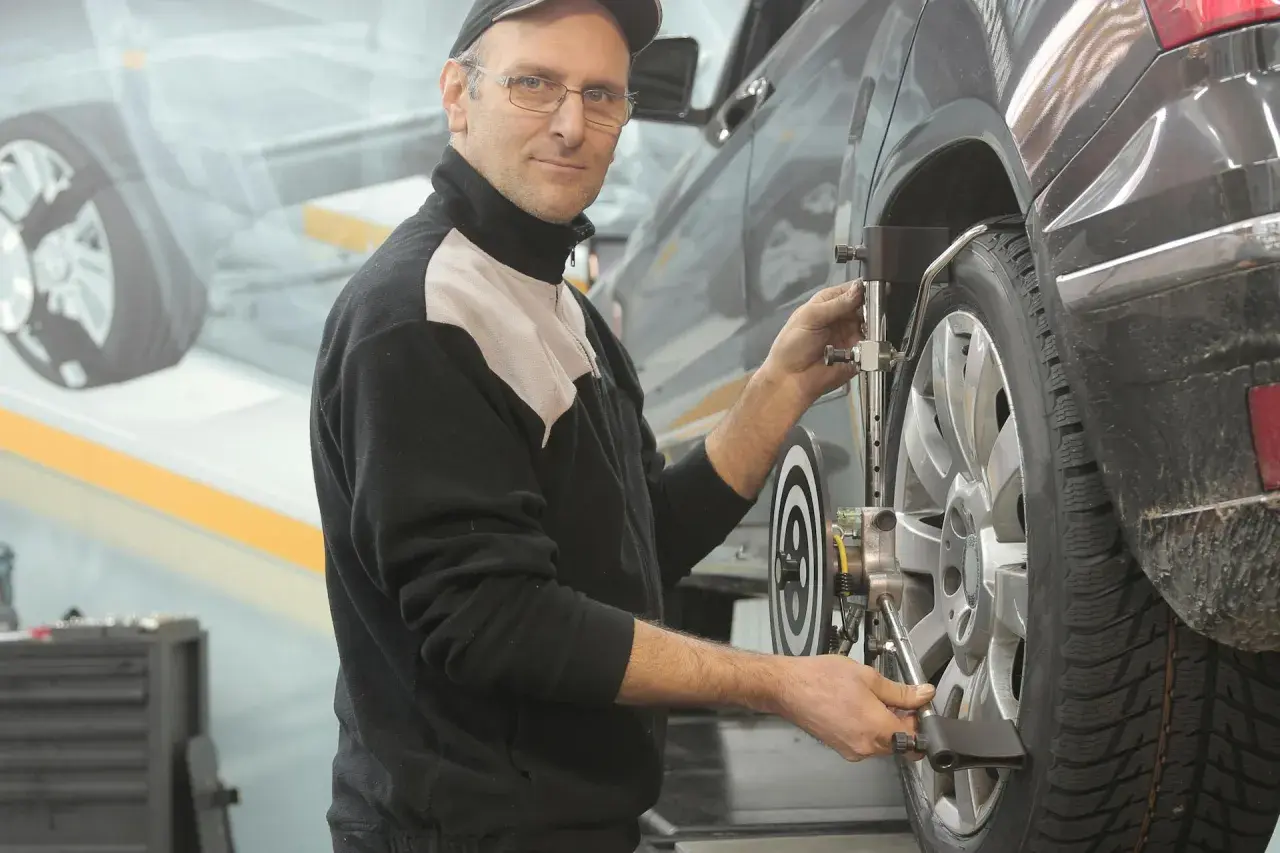 Mekaniker justerar hjulinställningen på en bil. Han ser till att allt är perfekt för att serva bilen.