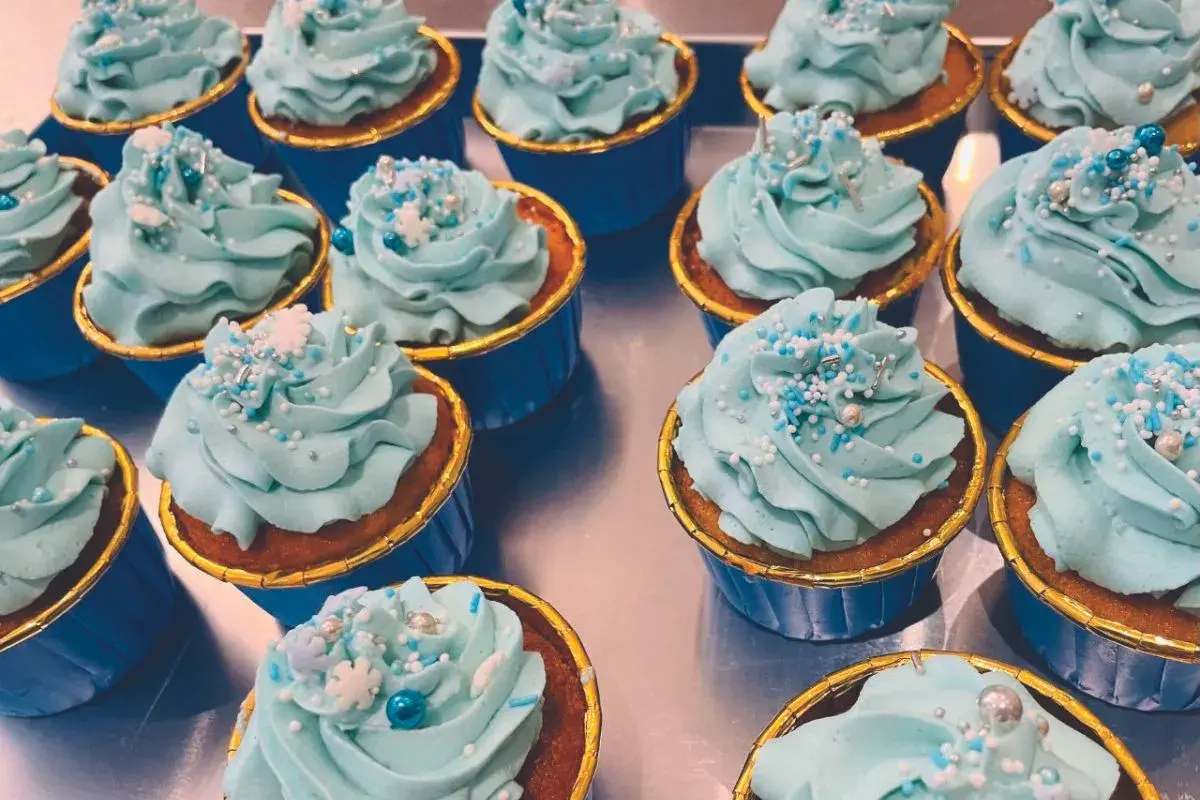 Una fila di cupcake con glassa azzurra e decorazioni a tema invernale. Una deliziosa cupcake ricetta pronta da gustare.