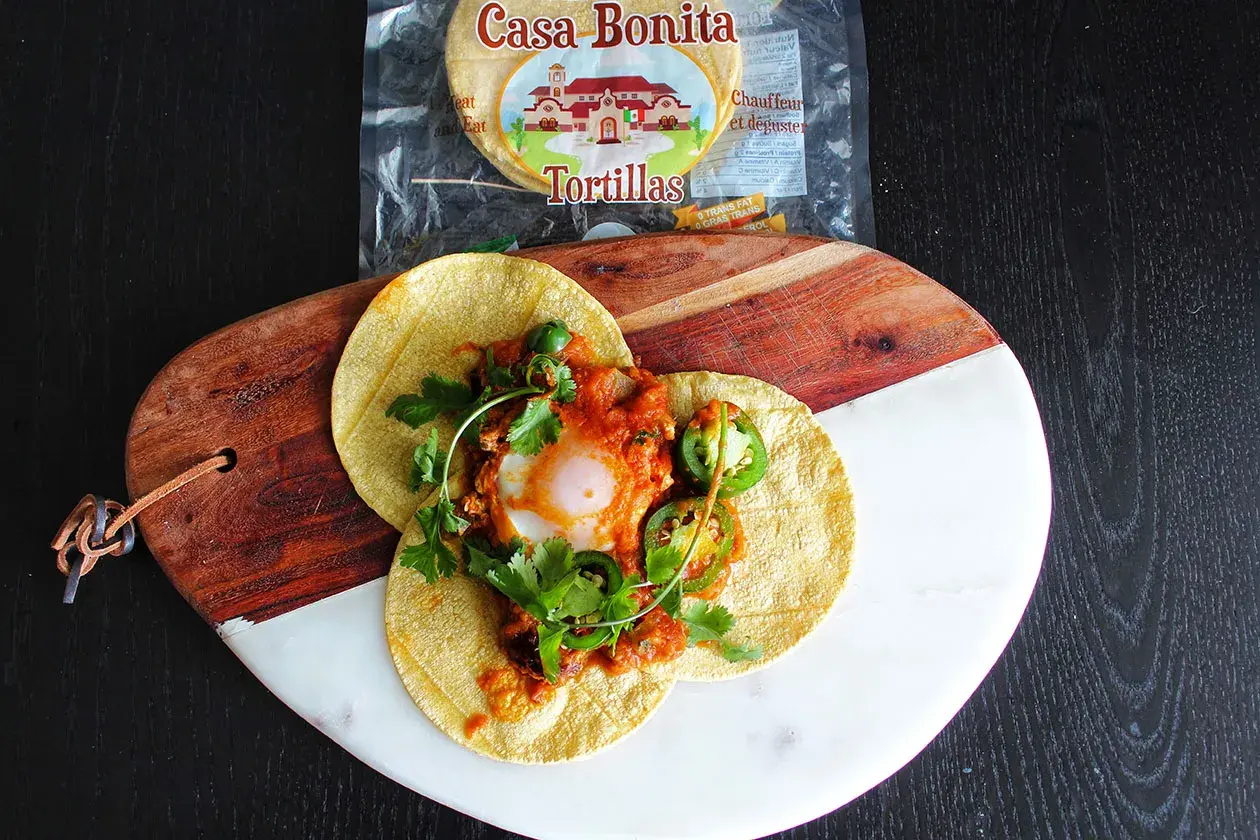 Délicieux huevos rancheros recette sur tortillas, garni d'un œuf coulant, sauce tomate épicée, jalapeños et coriandre fraîche.