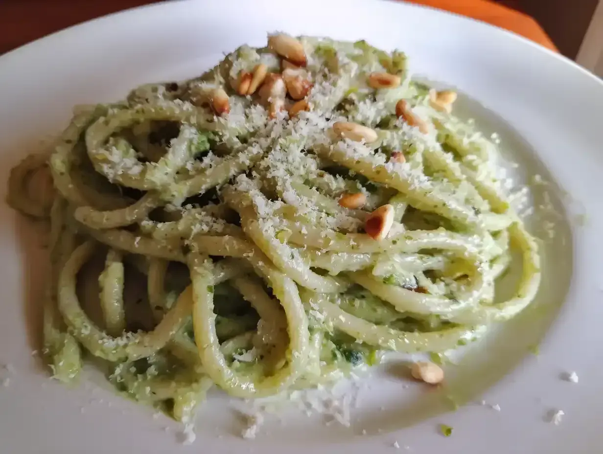 En tallrik med krämig pasta pesto, toppad med pinjenötter och riven parmesan. En härlig italiensk klassiker.
