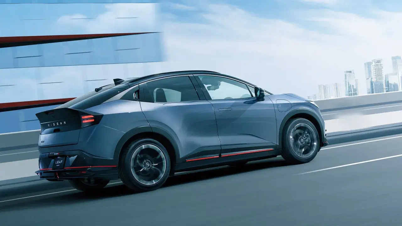 En blå Nissan Leaf 2026 glider fram på en motorväg med en stadssilhuett i bakgrunden.