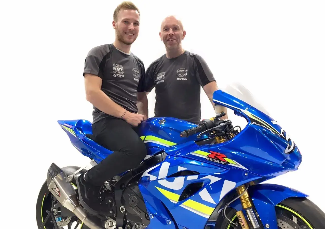 Davey Todd y su equipo posan junto a una moto Suzuki azul brillante.