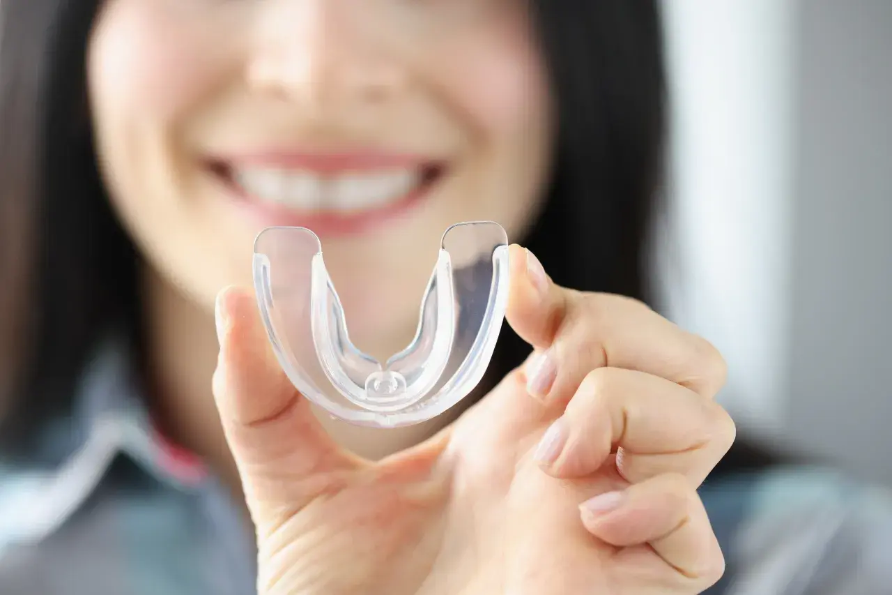 Donna sorride mostrando un bite trasparente. Scopri quanto costa un bite dal dentista per proteggere i tuoi denti.