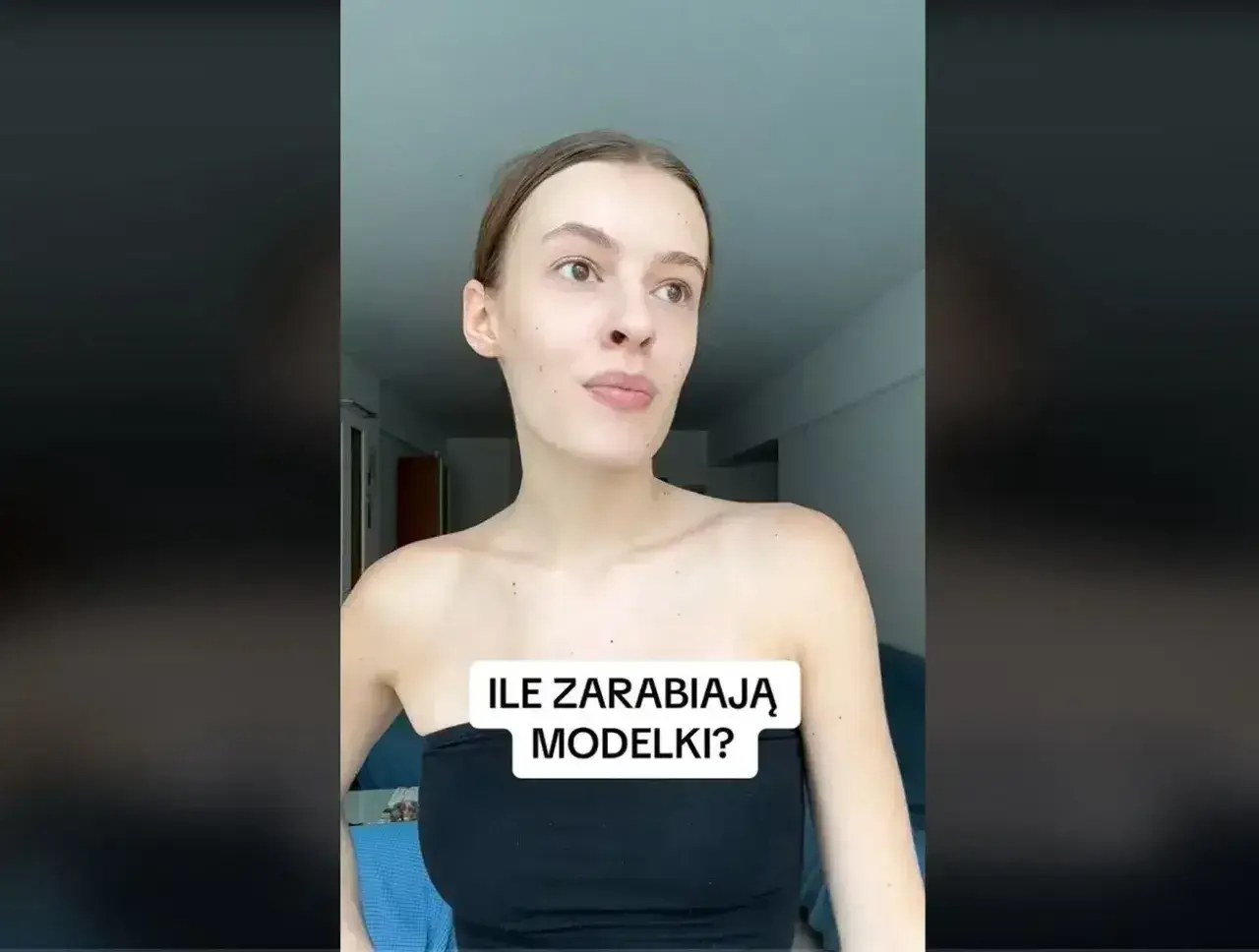 Młoda kobieta w czarnym topie zastanawia się, ile zarabia modelka w Polsce.
