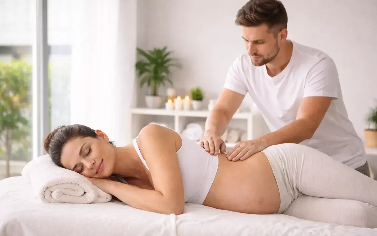 Donna incinta rilassata riceve un massaggio prenatale da un terapista esperto.