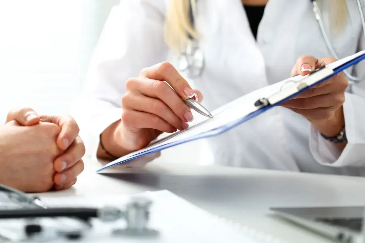 Lekarz rodzinny pisze skierowanie na rezonans. Pacjent czeka na diagnozę.