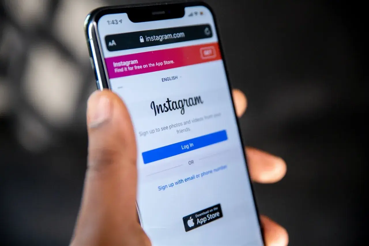 Dłoń trzyma smartfon z ekranem logowania Instagram. Dowiedz się, jak odzyskać skradzione konto na Instagramie, gdy widzisz ten ekran.