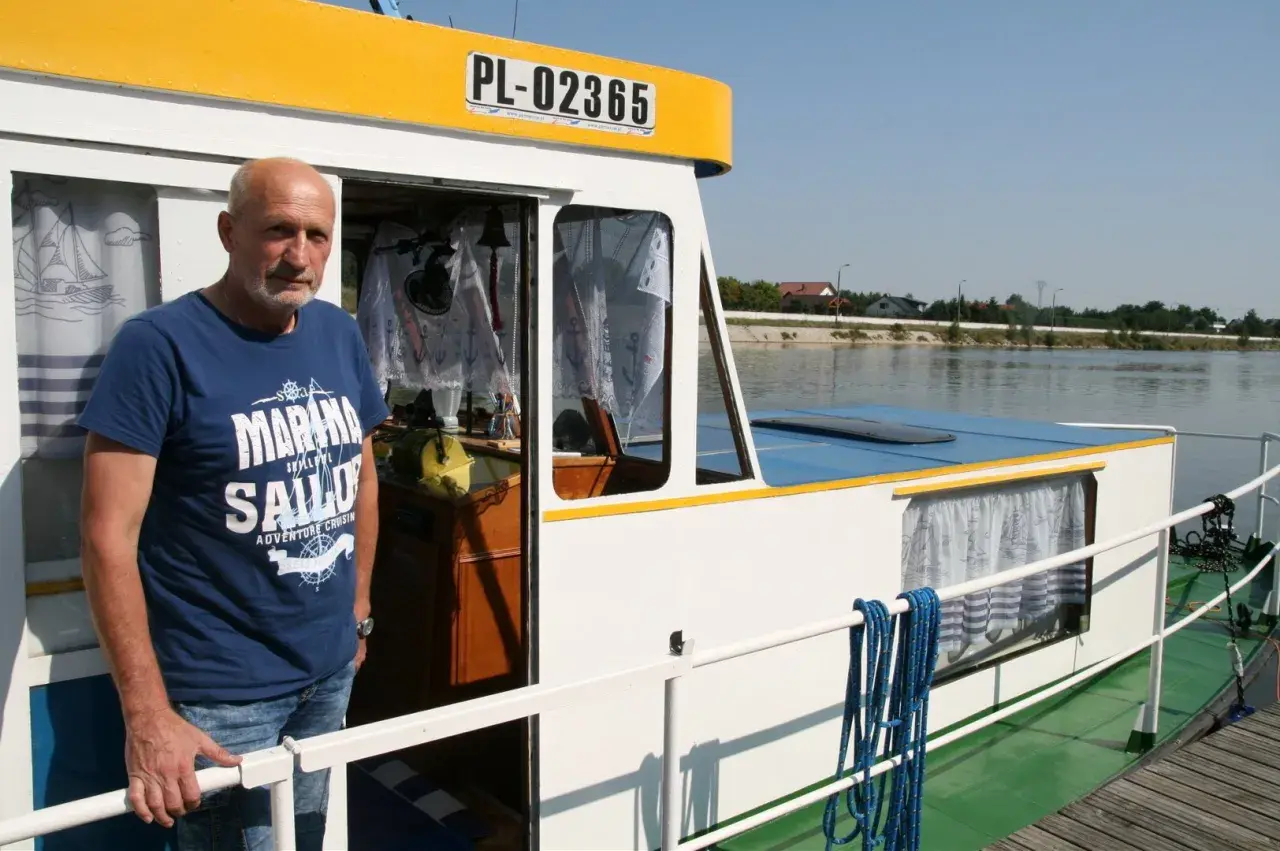 Mężczyzna na pokładzie statku, symbolizującego transport rzeczny. Widoczna tablica rejestracyjna PL-02365.