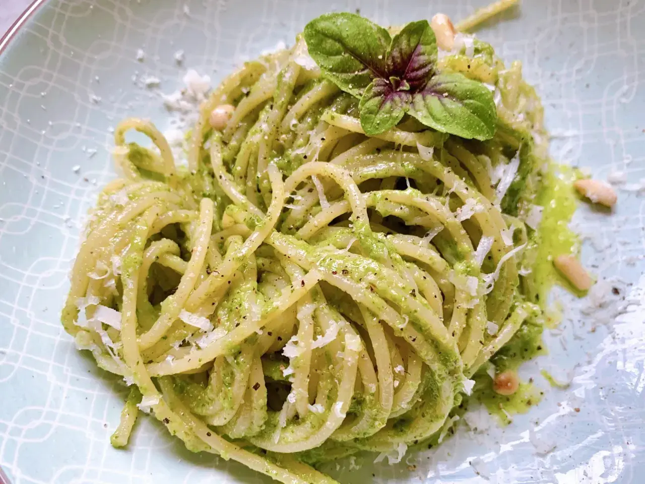 Ein Teller mit köstlichen Pesto Nudeln, garniert mit frischem Basilikum und Pinienkernen.
