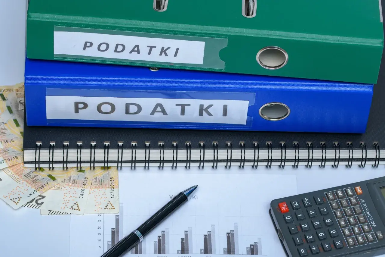 Segregator z napisem "PODATKI", pieniądze, kalkulator i wykres. Szukasz sposobu, jak zmniejszyć podatek za budynki gospodarcze?