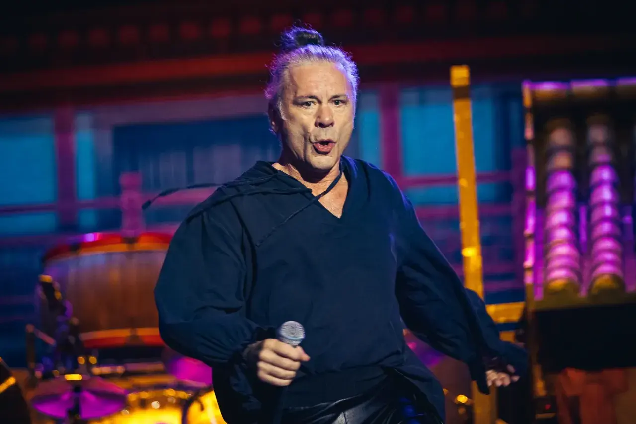 Bruce Dickinson, wokalista Iron Maiden, śpiewa z mikrofonem na koncercie.