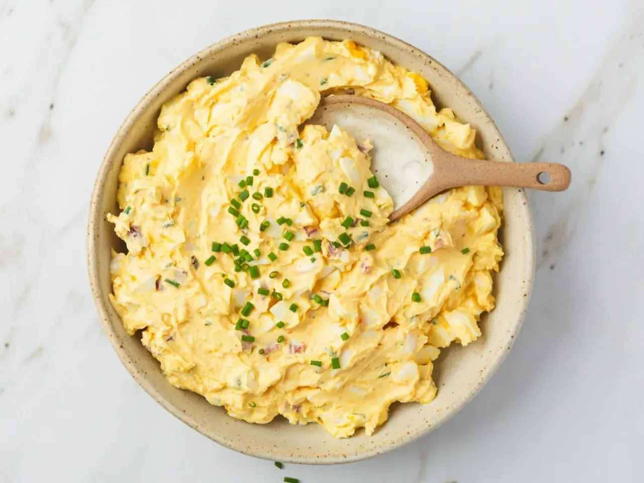 Kremowa pasta jajeczna z jogurtem, posypana szczypiorkiem, w ceramicznej misce. Idealna na kanapki.
