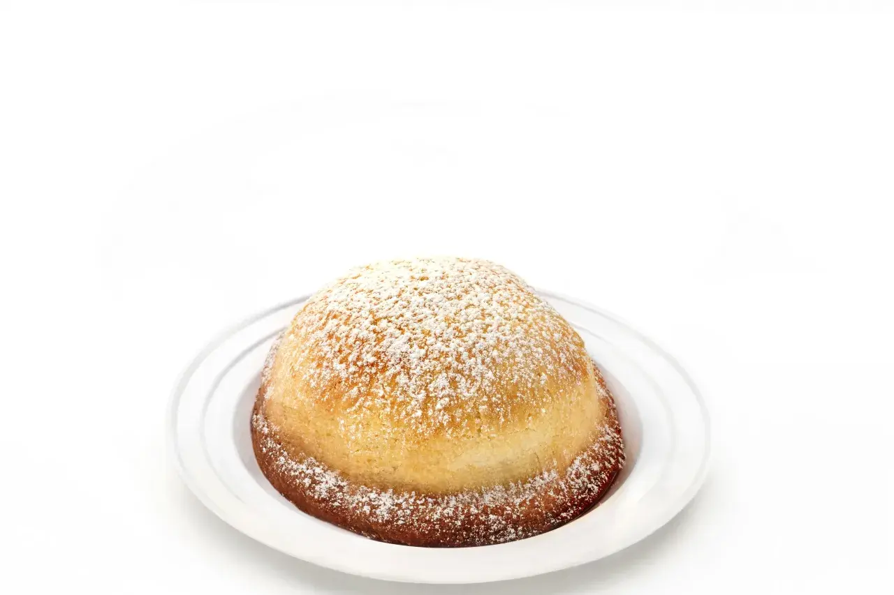 Sfogliatella frolla, un dolce napoletano dalla forma a conchiglia, cosparso di zucchero a velo su un piatto bianco.