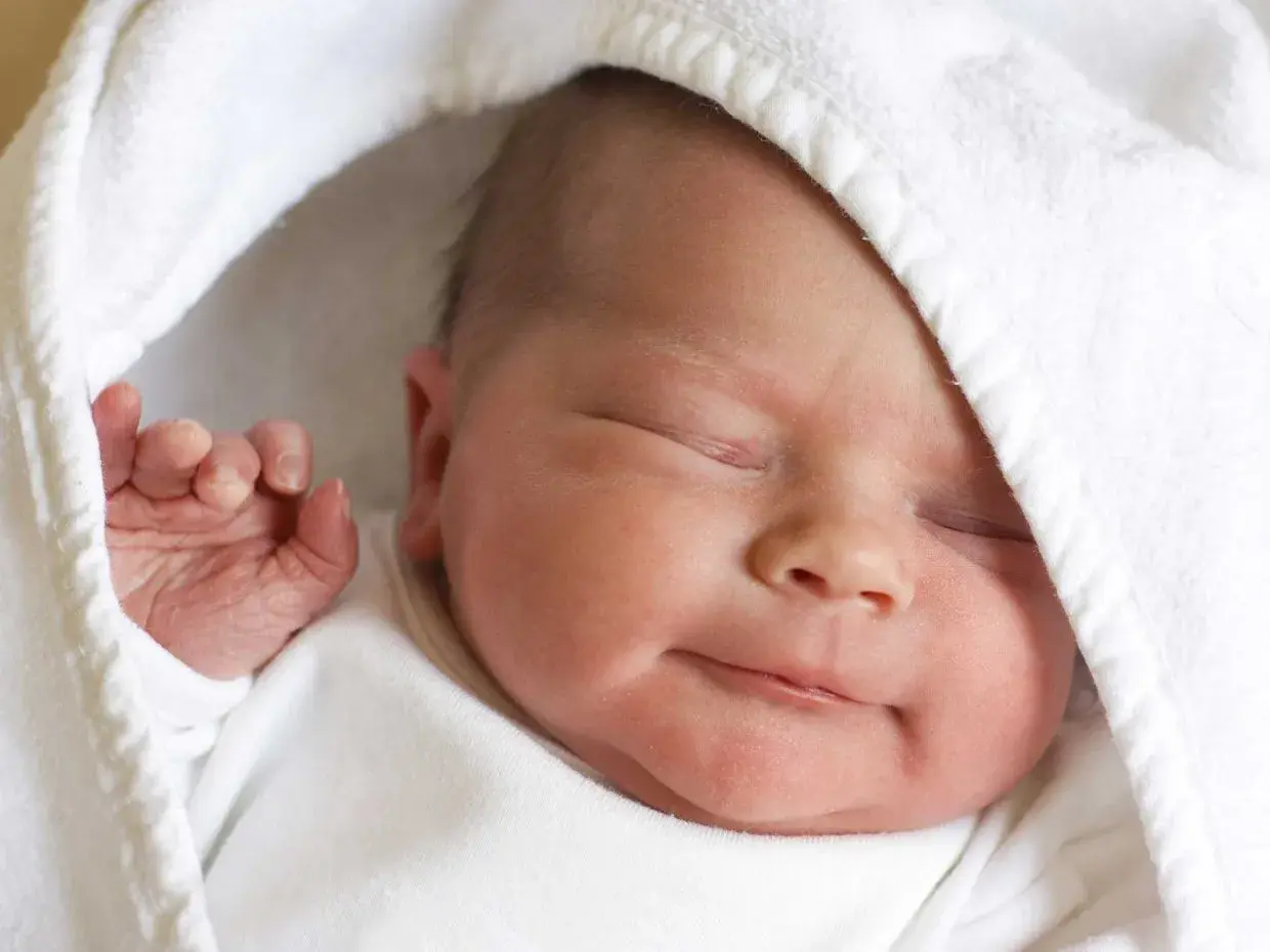 La morbida pelle neonato, avvolta in un soffice asciugamano bianco, dorme serenamente.