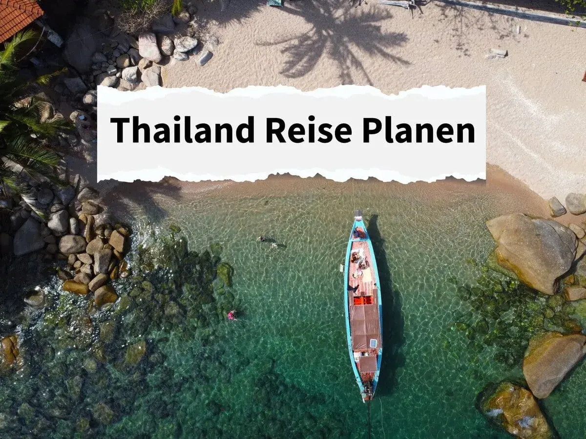 Traumhafte Bucht in Thailand mit Longtail-Boot und Badenden. Informiere dich über die **reisewarnung thailand aktuell**, bevor du deine Reise planst.