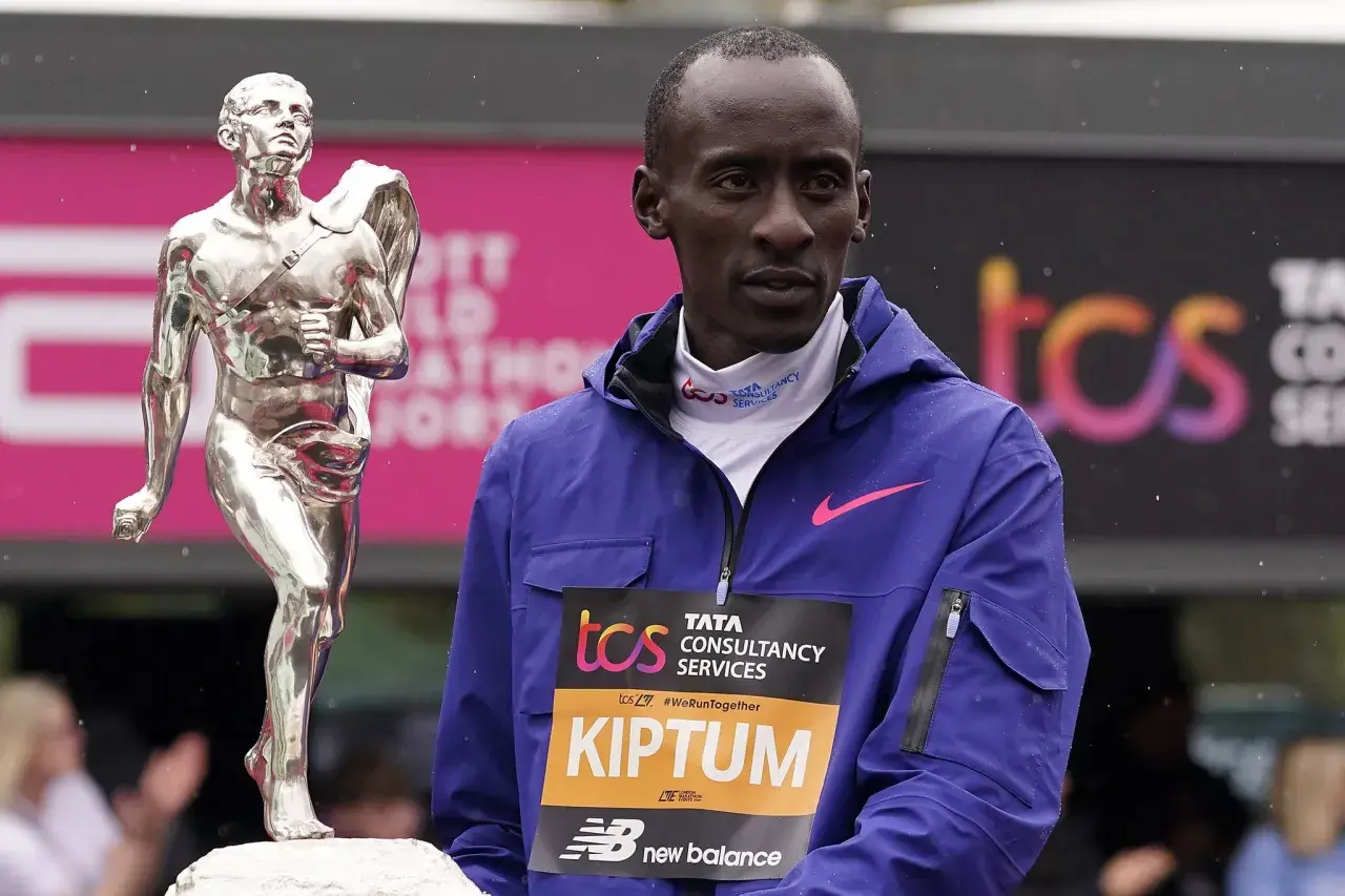 Kelvin Kiptum steht neben einer silbernen Trophäe, bereit für die Siegerehrung.