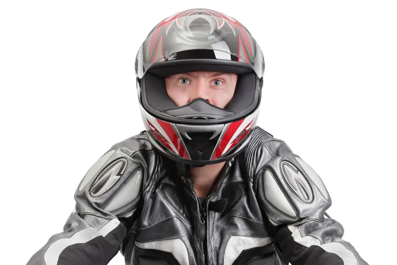 Occhi spalancati dietro un casco stretto, pronto per la corsa. La tuta in pelle grigia e nera completa il look da motociclista.