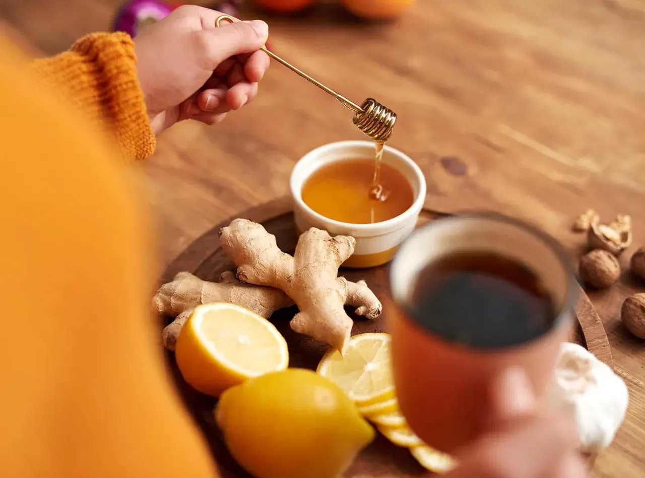 Zutaten für hustentee selber machen: Ingwer, Zitrone, Honig und eine Tasse Tee.