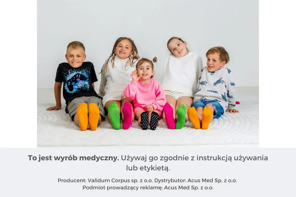 Pięcioro dzieci siedzi na podłodze, prezentując kolorowe skarpetki na stopach.