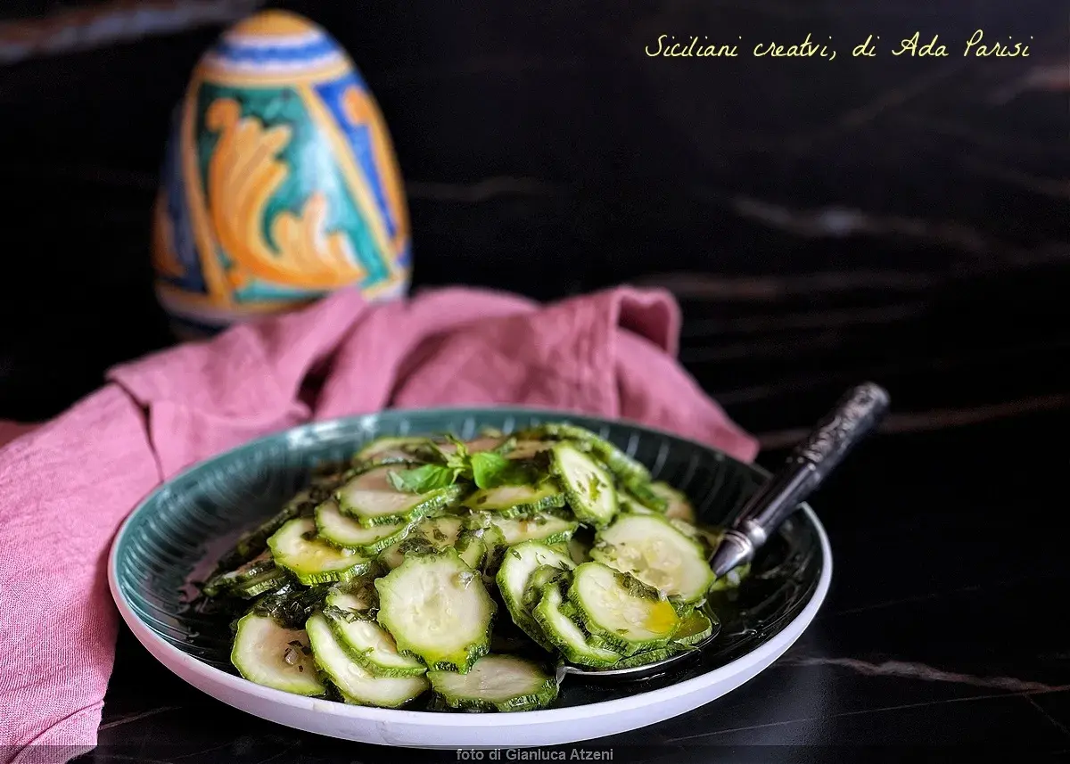 Assiette de courgettes marinées à l'italienne, garnie de basilic frais. Un plat sicilien créatif.