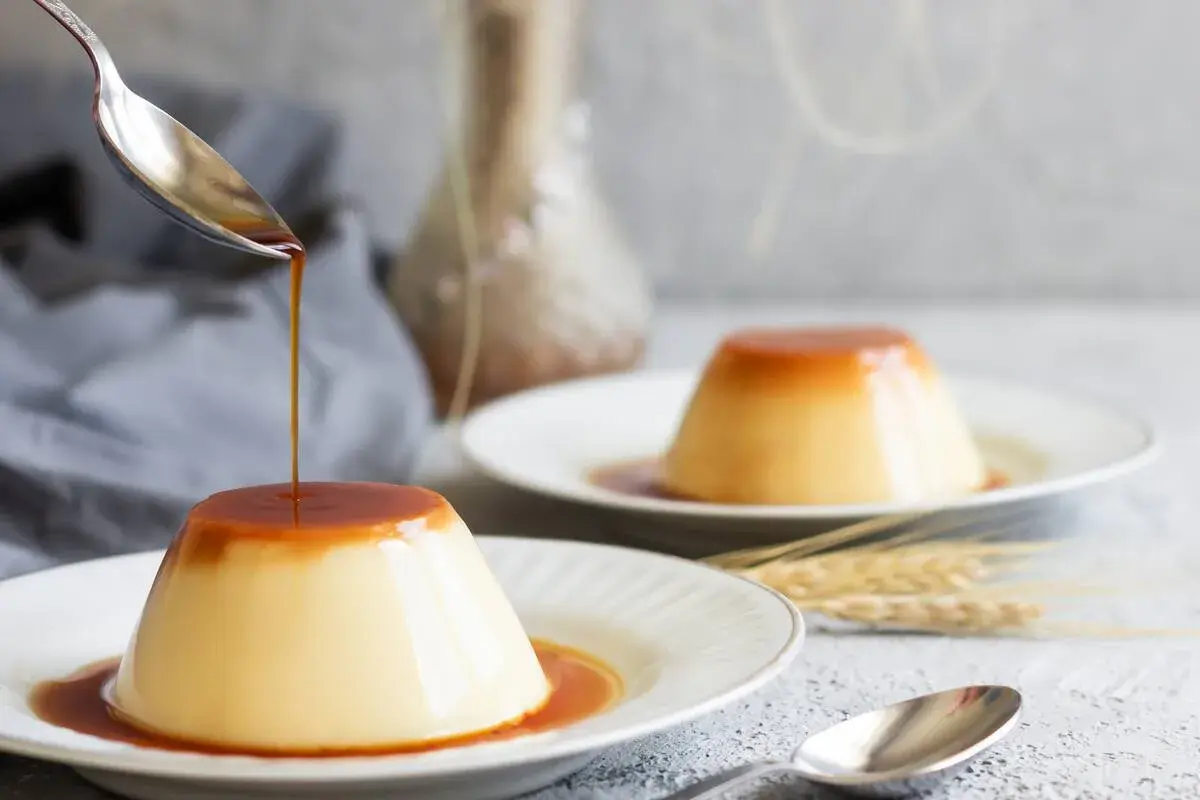 Delicioso flan de huevo con caramelo líquido cayendo de una cuchara. Una receta casera que enamora.
