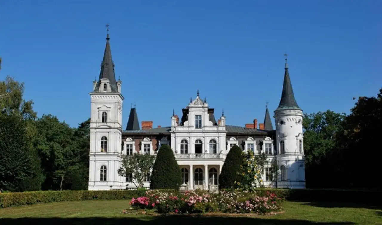 Imponujący pałac w Posadowie z wieżami i ozdobnym ogrodem.