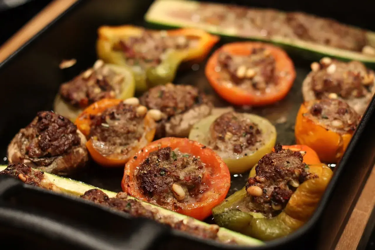 Délicieux légumes farcis, tomates, poivrons et courgettes, garnis d'une savoureuse farce à la viande et aux pignons.
