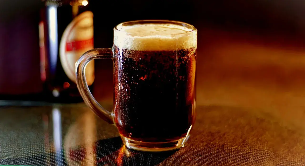 Chłodny, ciemny lager z gęstą pianką w szklanym kuflu, obok butelki.