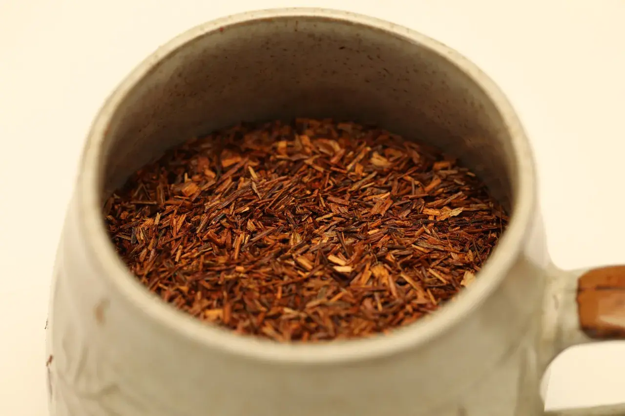Czerwona herbata rooibos w ceramicznym kubku, idealna na relaksujący wieczór.