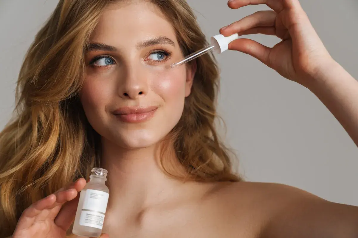Młoda kobieta aplikuje serum z pipetką na twarz. Czy to peptydy?