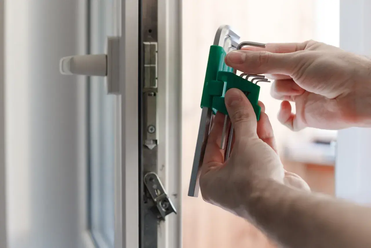 Dłonie trzymają zestaw kluczy imbusowych przy okienku. Dowiedz się, jak sprawdzić producenta okna, szukając oznaczeń.