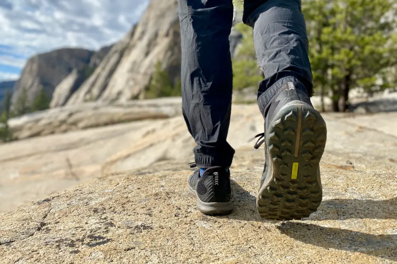 Close-up of hiking boots on a rocky trail, showcasing the aggressive boot tread patterns designed for grip on uneven terrain.