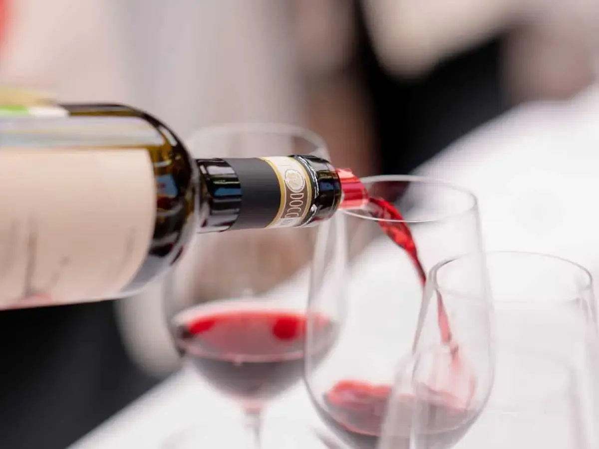 Versando vino rosso da una bottiglia in calici, un'esperienza dei migliori vini Chianti.