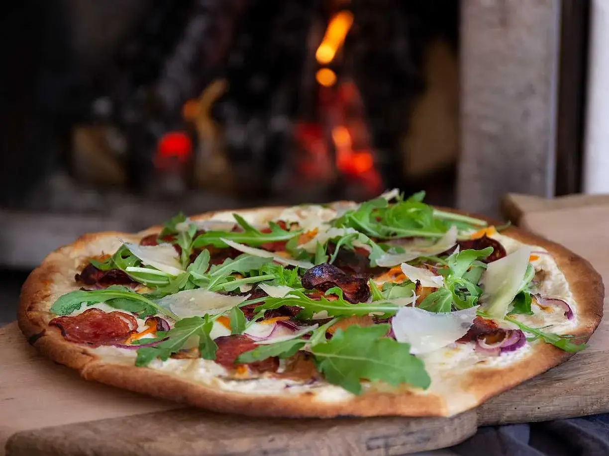 Pizza bianco med salami, ruccola och parmesan. En läcker pizza som precis kommit ut ur ugnen.