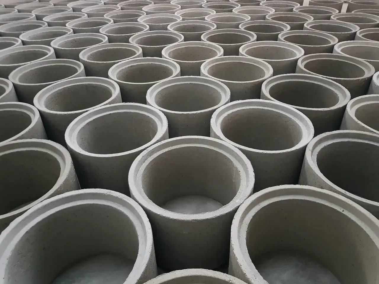Rzędy betonowych kręgów, gotowych do budowy studni kręgowej.