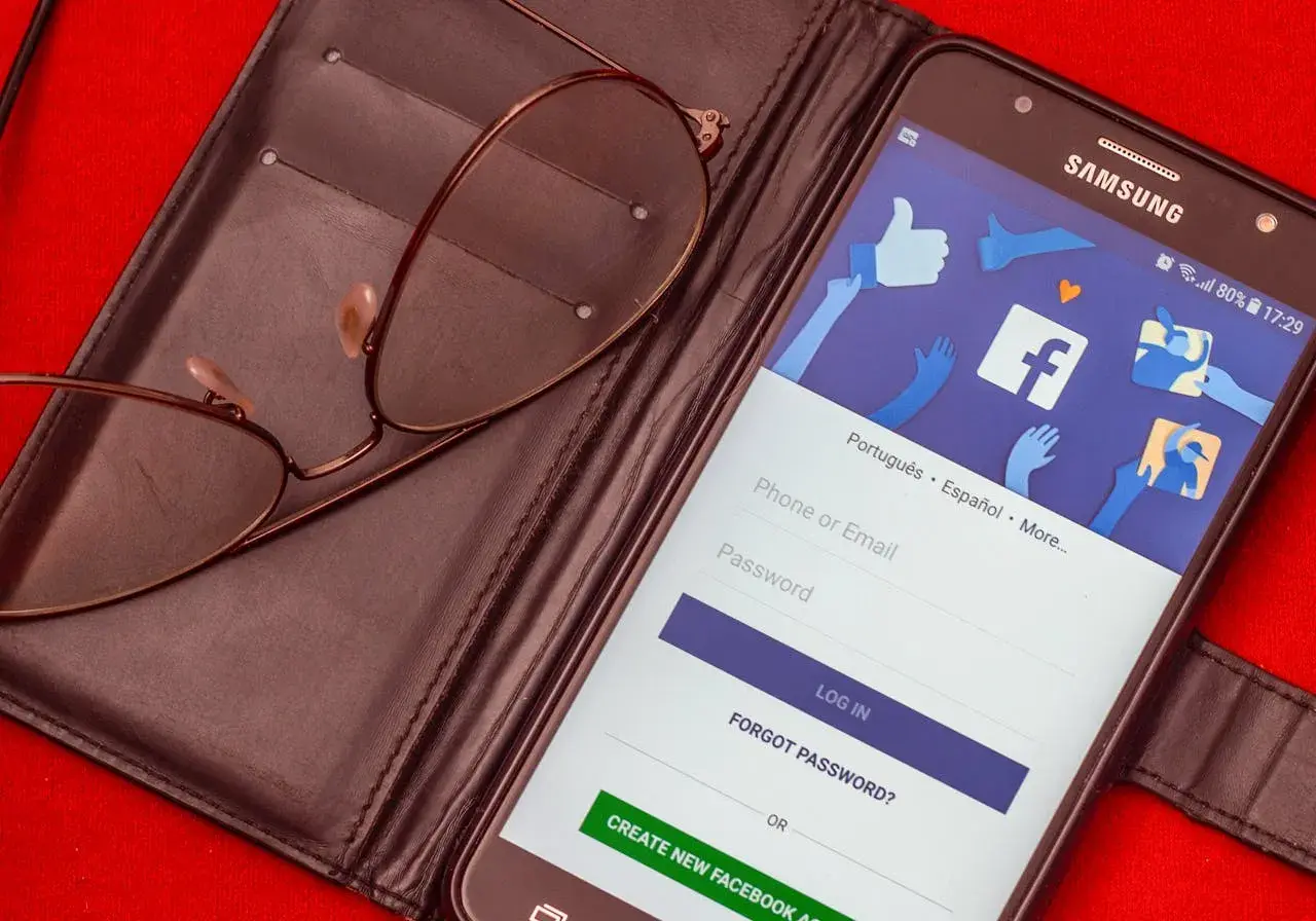 Okulary na etui, telefon z ekranem logowania Facebook. Chcesz wiedzieć, jak zmienić numer tel na FB?
