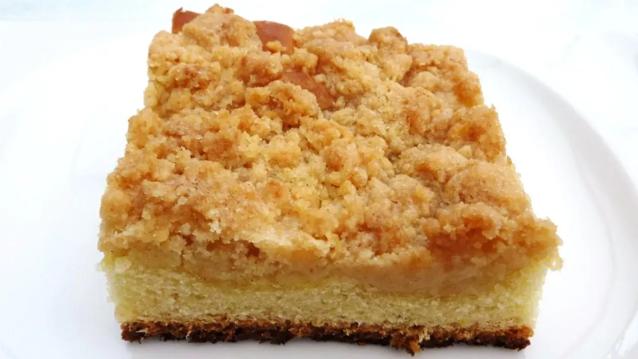 Ein Stück saftiger Streuselkuchen vom Blech mit goldbraunen, knusprigen Streuseln auf hellem Teig.