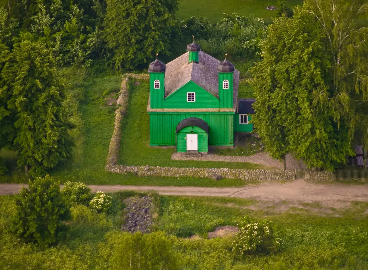 Zielona, drewniana meczet, serce tatarskiej wioski, otoczona bujną zielenią.