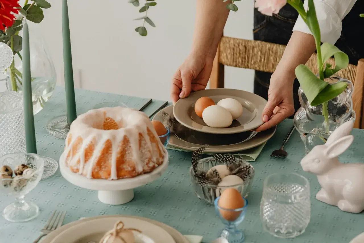 Tavola apparecchiata per Pasqua con un ciambellone glassato, uova e decorazioni. I dolci pasquali sono pronti per essere gustati.