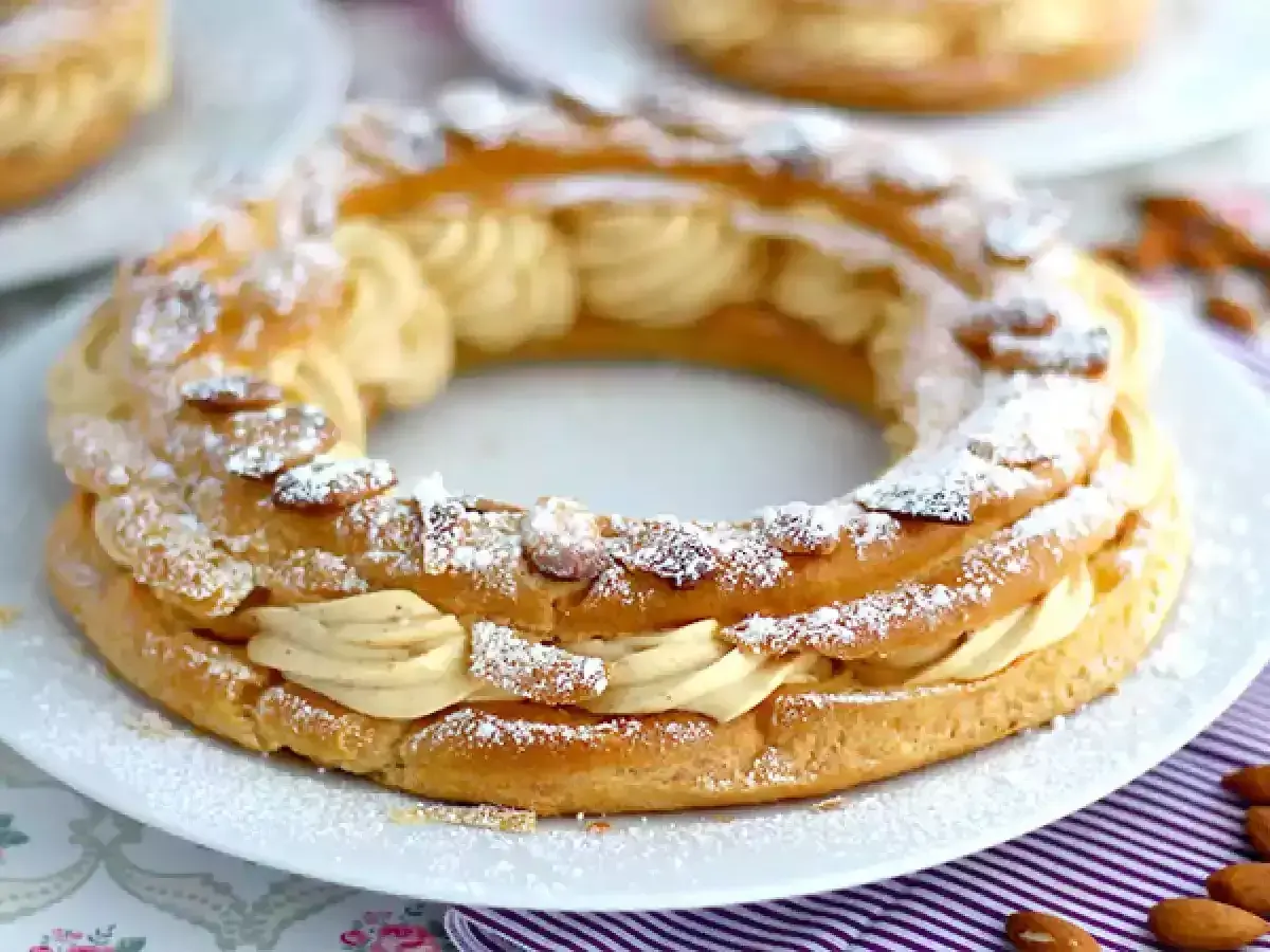 Un Paris-Brest, pâtisserie en forme de couronne, garni d'une crème onctueuse et saupoudré d'amandes effilées et de sucre glace.