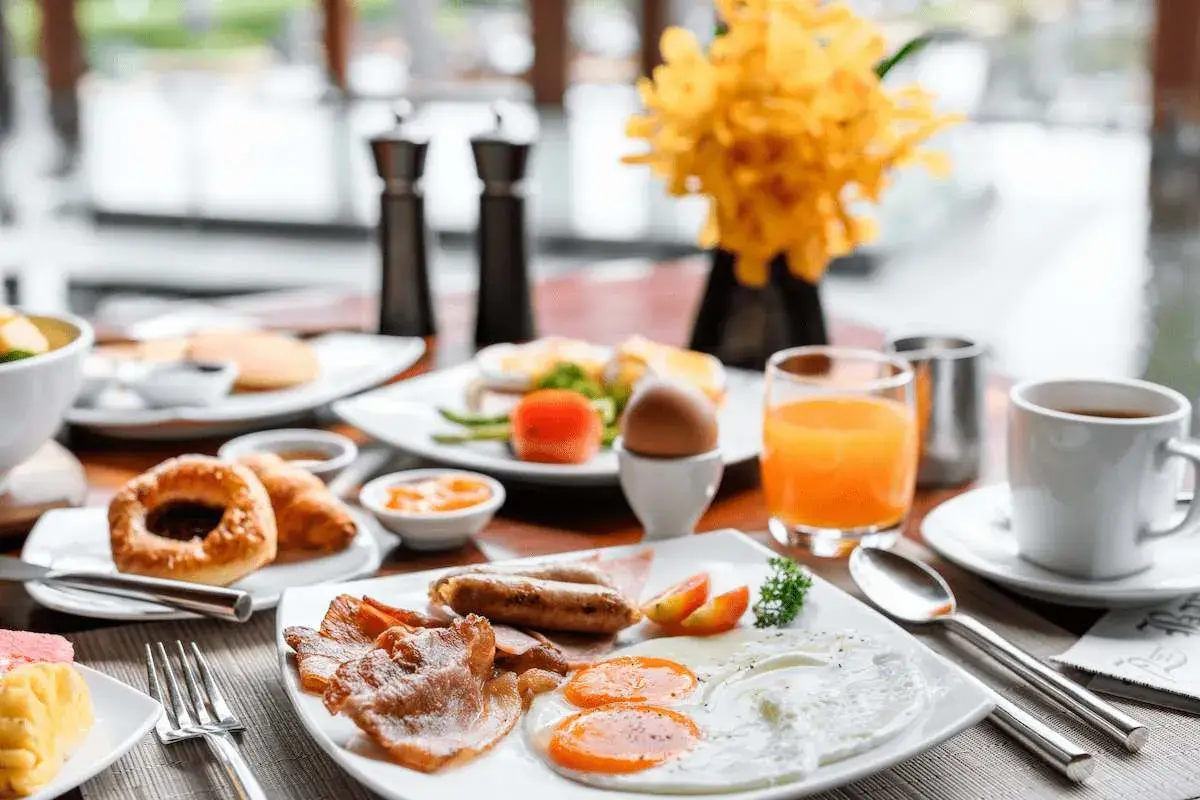 Desayuno completo con huevos, salchichas, tocino y jugo de naranja. ¡Ideal para empezar el día de tu vuelo+hotel todo incluido baratos!
