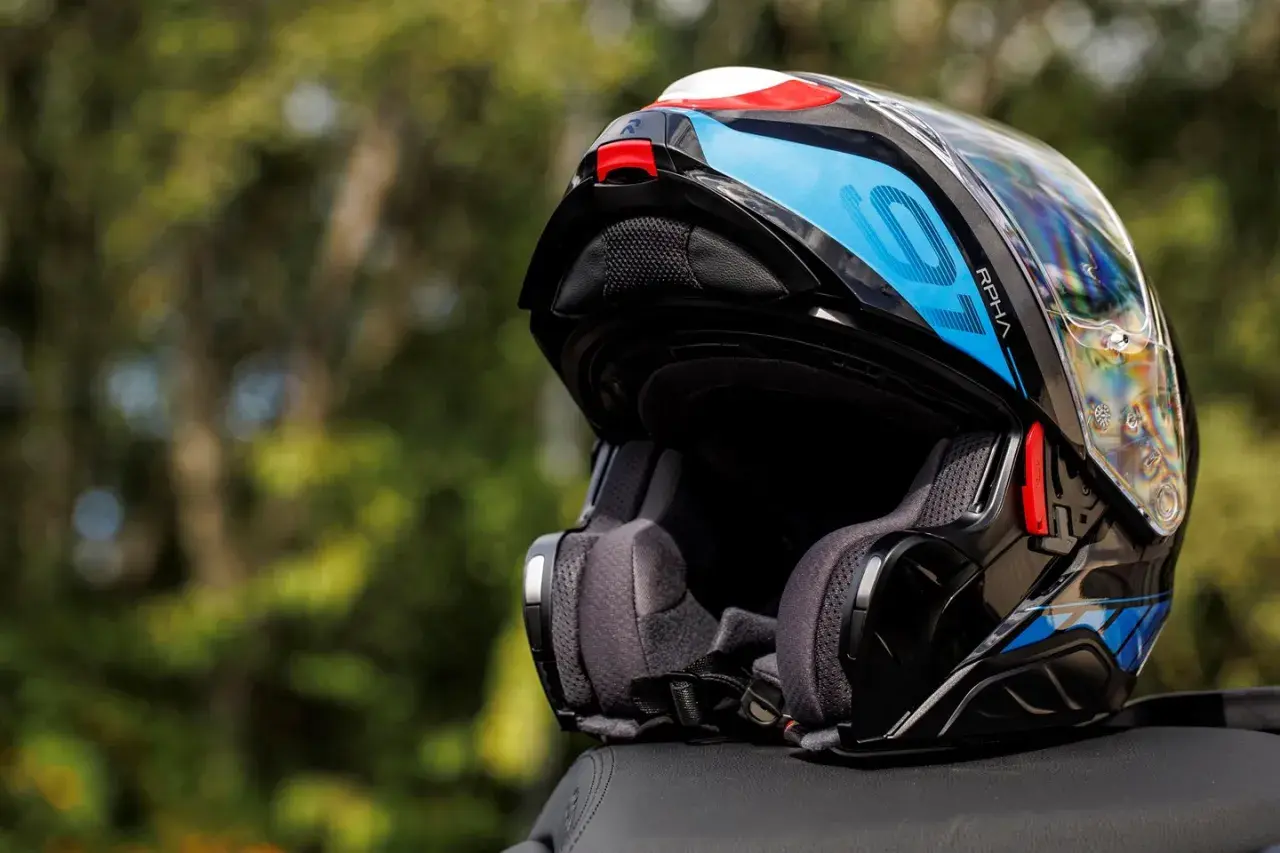 Kask motocyklowy RPHA 91 w kolorze czarnym z niebieskimi i białymi akcentami, gotowy na kolejną podróż.