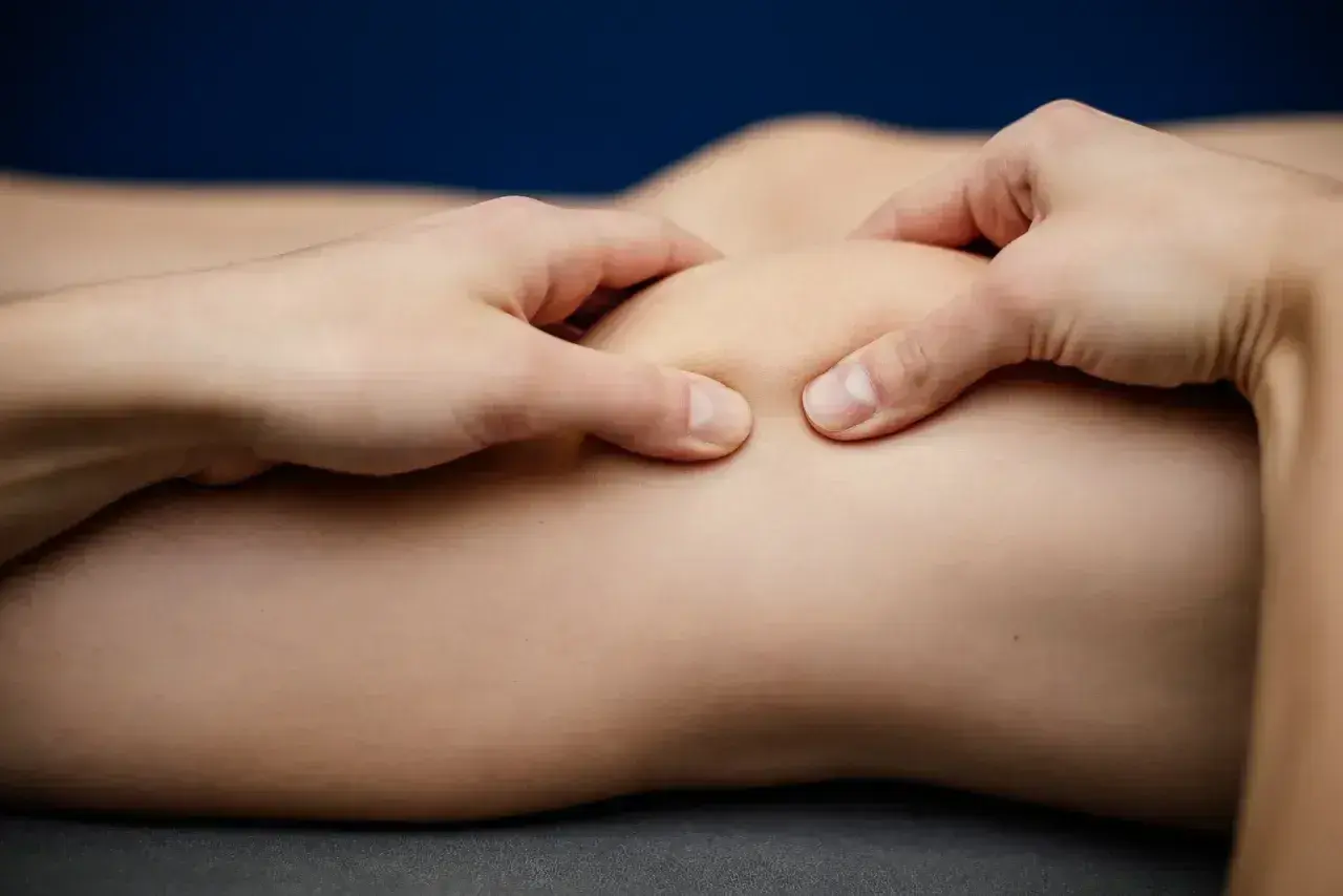 Fizjoterapeuta wykonuje masaż rzepki, kluczowy element rehabilitacji rzepki ćwiczenia.