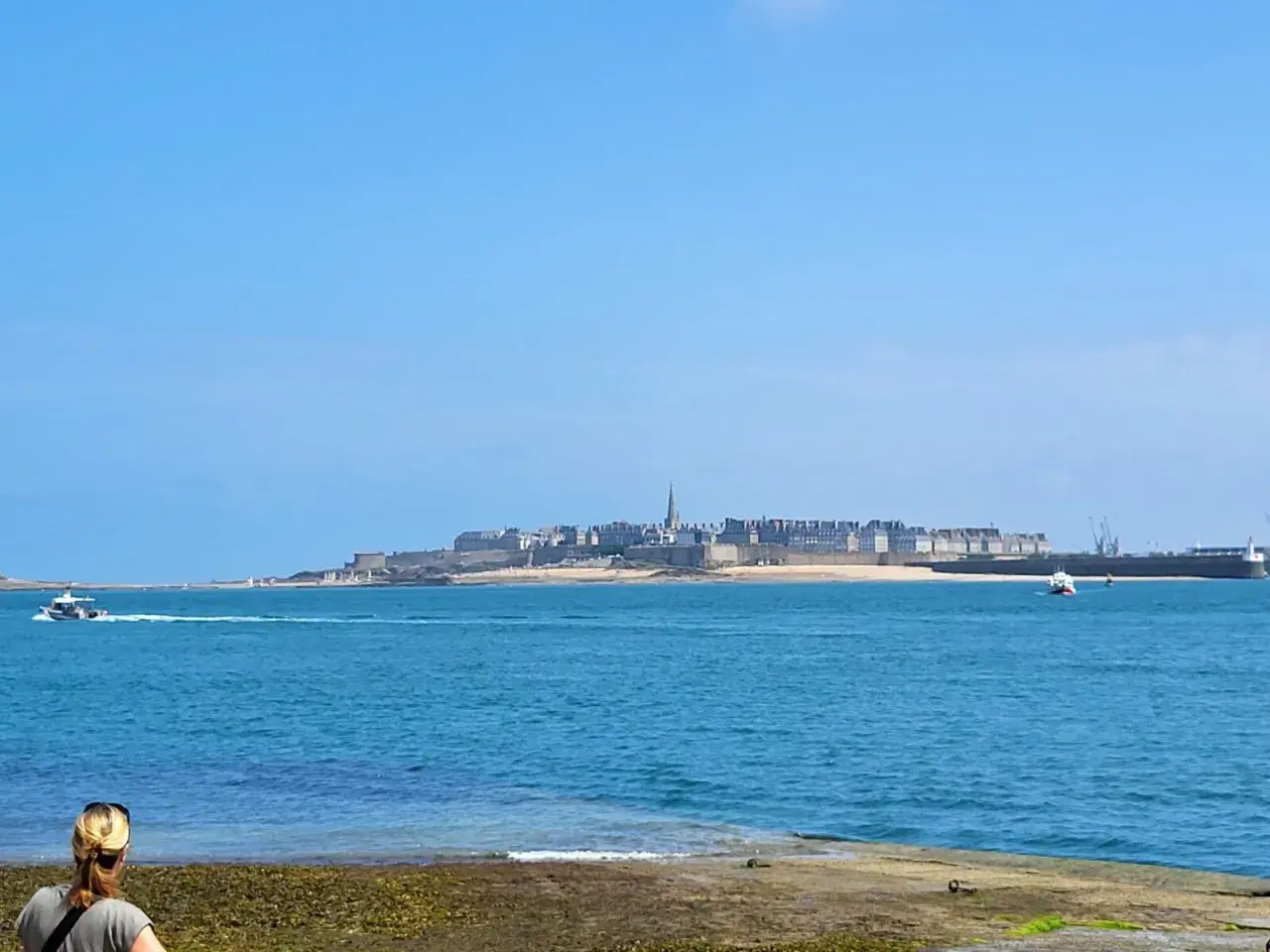 Une personne admire la vue sur la ville fortifiée, une belle journée pour une randonnée le long de la Rance.