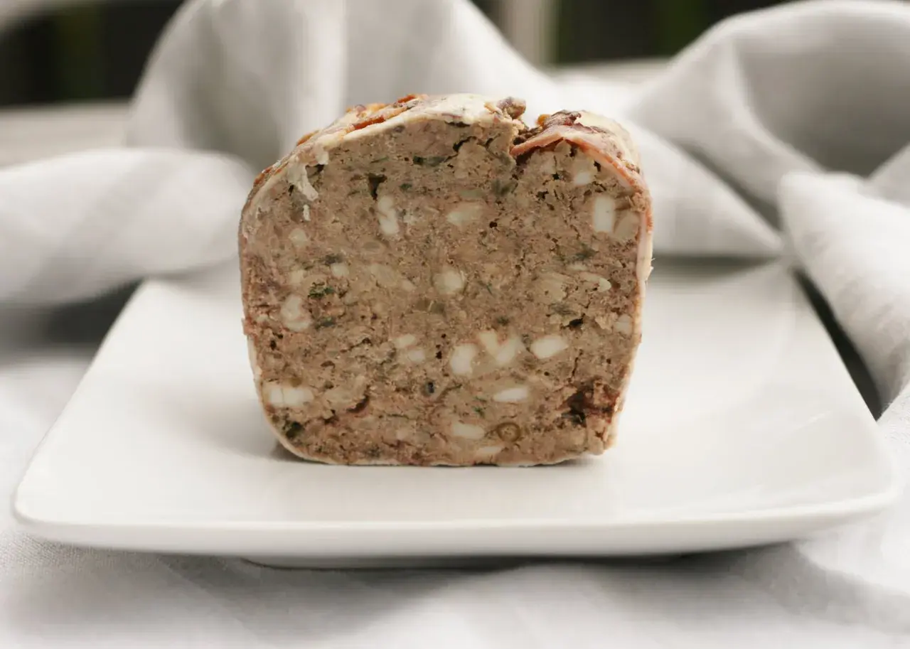 En bit rustik lantpaté med synliga bitar av fett och örter, perfekt för ett lantpaté recept.