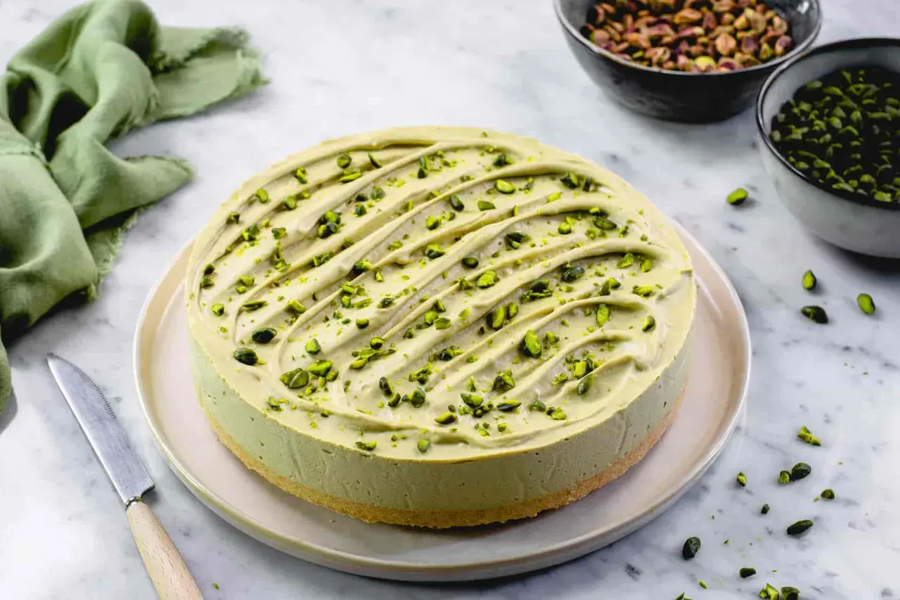 Delizioso cheesecake al pistacchio, guarnito con granella verde brillante. Un tripudio di gusto e colore.