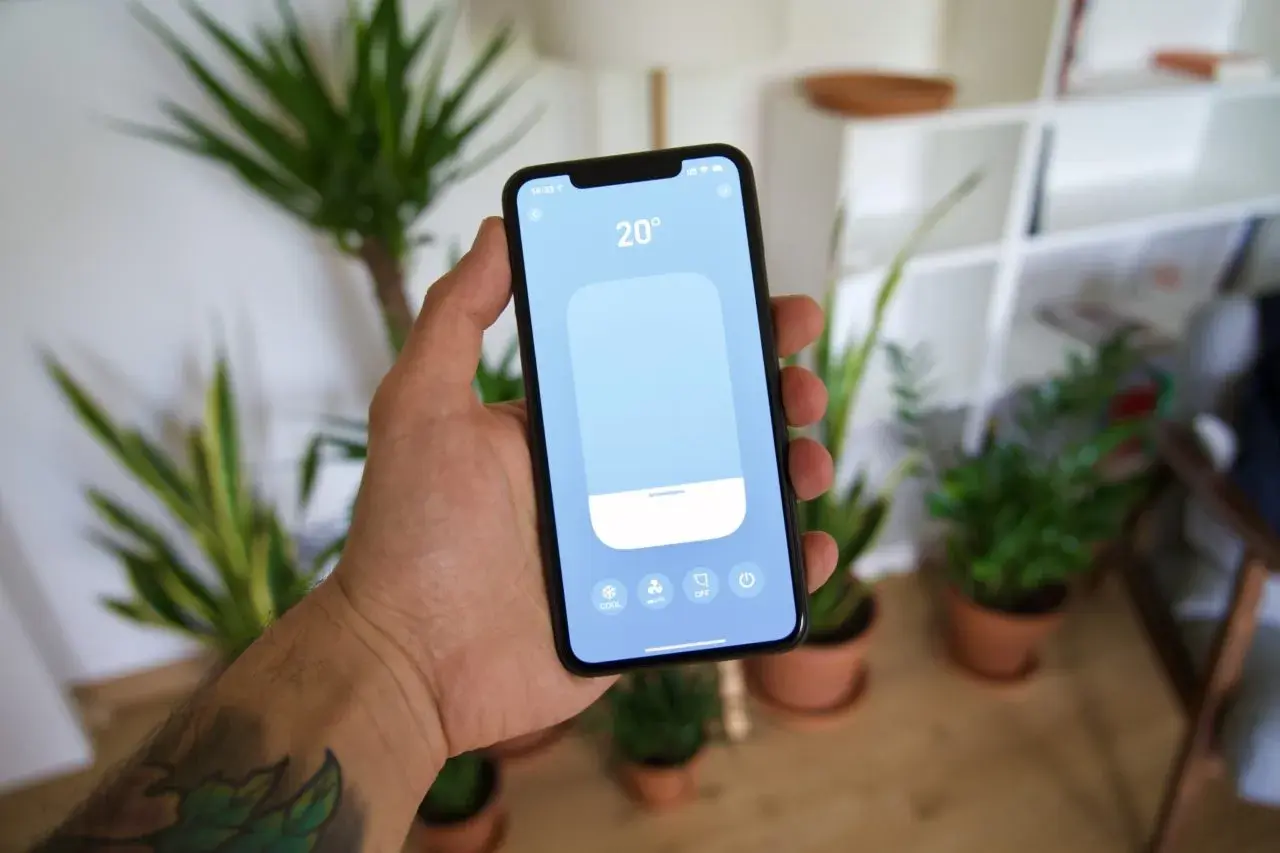 Main tenant contrôle la température de sa maison avec une application tado homekit sur son smartphone.