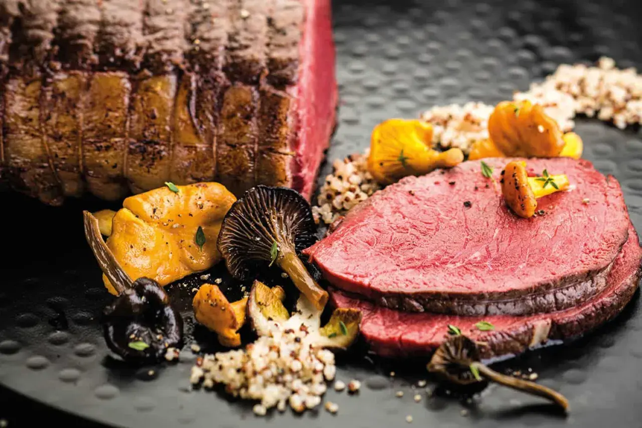 Zarter Rinderbraten im Ofen, perfekt geschnitten, serviert mit Pilzen und Quinoa. Ein Festmahl!