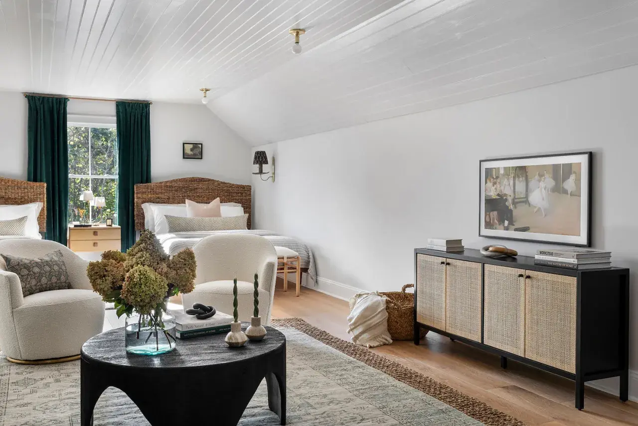 A cozy bedroom with a mix of dark and light wood furniture, featuring rattan headboards, a dark wood cabinet, and light wood nightstands.